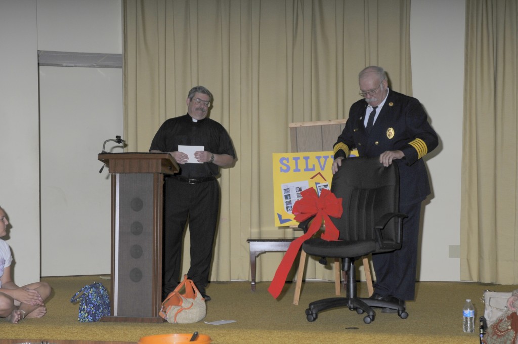 Pastor Kendall receiving his new office chair from Fire Chief George Gettler